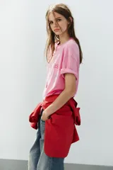Camiseta oversize de algodón color rosado, con efecto lavado, cuello redondo y manga corta. Presenta aplicaciones de brillos con motivos de Hello Kitty y amigos.