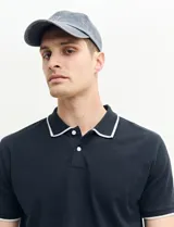 Remera polo azul marino con ribetes blancos en el cuello y en los bordes de las mangas corta, y cierre frontal de botones.