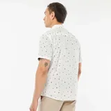 Camisa blanca de corte recto y manga corta, con estampado de palmeras, estrellas y lunas en color negro.