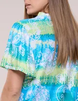 Blusa de rayón en tonos turquesa y verde, con cuello en V con detalles bordados, mangas cortas amplias y diseño estampado con motivos florales y geométricos.