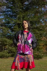 Chaqueta negra con estampado de hojas en tonos rosa, violeta y marrón. Diseño acolchado con cuello clásico y cierre frontal con botones.