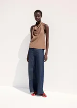 Pantalón de jean azul oscuro con corte recto y tiro medio. Presenta costuras verticales marcadas en el frente de cada pierna y diseño de pierna ancha.