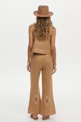 Pantalón camel de lino, de corte recto y tiro alto, con detalles bordados en la parte inferior de las piernas.