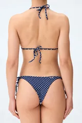 Top de bikini tipo triángulo en color azul marino con estampado de lunares blancos, tiras ajustables al cuello y a la espalda, y detalle de cuentas blancas en el centro.