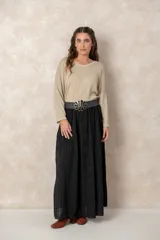 Pollera larga de color negro con textura plisada y corte amplio. Cuenta con una cintura elástica y un cinturón decorativo con hebilla floral en el centro.