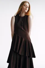Vestido midi sin mangas, color marrón oscuro, con cuerpo entallado de punto y falda de satén con volados escalonados y diseño asimétrico.