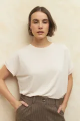 Remera color beige de manga corta con cuello redondo y detalle de pliegues en los hombros.