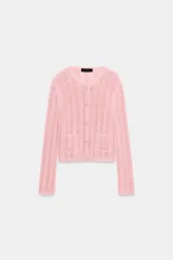 Chaqueta de punto pointelle en color rosado, con cuello redondo, manga larga y bolsillos delanteros de parche. Cuenta con cierre frontal de botones claros.