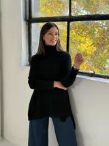 Sweater de punto color negro con cuello alto tipo polera, diseño holgado y corte asimétrico con la parte trasera más larga.