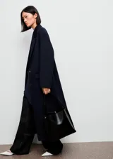 Abrigo largo de corte recto confeccionado en tejido mezcla de lana. Presenta cuello con solapas de muesca, cierre frontal de dos botones y dos bolsillos laterales con solapa.