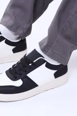 Championes urbanos de diseño minimalista en color blanco, con cordones al tono y suela de goma plana. Presentan perforaciones decorativas en la puntera y costuras reforzadas en los laterales.