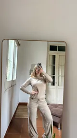 Pantalon de corte recto y holgado, confeccionado en tejido de punto acanalado color beige. Presenta cintura elástica con cordón ajustable y bolsillos laterales.