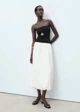 Vestido midi de diseño combinado con cuerpo tipo strapless en color negro y falda estilo globo en color blanco. Presenta un bajo abullonado y forro interior de algodón.
