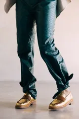 Mocasines de cuero en color dorado con detalles en marrón, con diseño bicolor y costuras artesanales expuestas en el empeine.