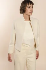 Chaqueta de sastrería color crema, entallada y con cuello erguido. Prenda forrada de lana fina sin teñir.