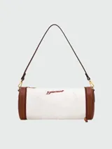Bolso tipo shoulder bag de Longchamp, modelo Épure Surf XS. Diseño cilíndrico en color blanco con detalles en cuero marrón en los extremos y cierre de cremallera. Incluye correa fina de hombro y el logotipo de la marca impreso en el lateral.