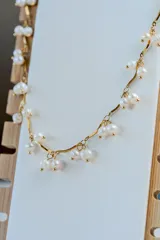 Collar de cadena dorada con diseño de eslabones curvos y perlas naturales colgantes distribuidas a lo largo de toda la pieza.