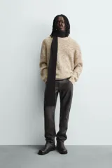 Jersey de punto con textura acanalada y diseño jaspeado en tonos beige y amarillo. Presenta un corte relajado, cuello redondo y mangas largas con acabados en rib.