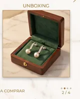 Caravanas colgantes de plata con diseño curvo adornado con circonias y rematadas con una perla blanca.