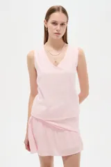 Musculosa de viscosa color rosado, con diseño broderie, breteles anchos, cuello en V y corte holgado.