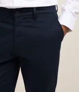 Pantalón slim de sastrería de color gris claro, confeccionado en sarga de algodón con elastano, con cierre frontal de botón y cremallera, y bolsillos.