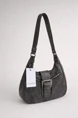 Cartera de hombro de tamaño compacto con acabado texturizado efecto cuero desgastado. Presenta un diseño con cierre superior, bolsillos frontales con cierre y una solapa central decorativa con hebilla metálica. Incluye asa fija para llevar al hombro.