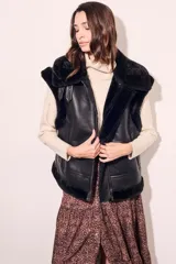 Chaleco negro de cuero sintético con cuello de piel sintética y cierre frontal con cremallera.