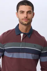 Remera polo de manga larga con cuello azul marino y solapa blanca. Presenta un diseño de rayas horizontales en tonos bordó, verde oscuro, blanco, azul marino y azul claro. Incluye un logo bordado en el pecho.