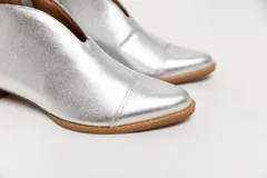 Botín de cuero color borgoña con taco bajo, corte en V en el empeine, pulsera con detalles metálicos y cierre lateral.