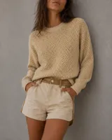 Short de gabardina color beige con detalles de costuras y paneles laterales en color tostado, diseño de tiro medio con cierre frontal y bolsillos laterales.