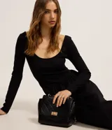 Vestido midi negro con parte superior de rib acanalado, escote en U y mangas largas. La falda es de tricolina lisa.