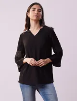 Blusa negra de gasa bambula con cuello a la base y escote en V. Tiene mangas 3/4 amplias con apliques de crochet.
