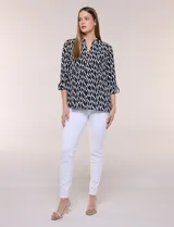 Blusa de calce suelto y caída ligera en color negro con estampado geométrico blanco. Presenta escote en V, cuello mao, abotonadura frontal metálica y bolsillos superiores en el pecho. Cuenta con mangas largas regulables con presilla y botón, ruedo redondeado con tajos laterales y canesú en la espalda.