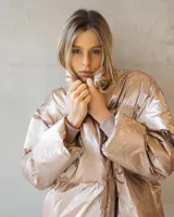 Campera puffer de corte oversize en tono champagne metalizado, con cuello alto envolvente y acabado brillante.