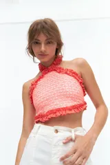 Top de escote halter confeccionado en broderie de algodón y bordado con hilo color coral. Enmarcado con voladitos de lino a tono.