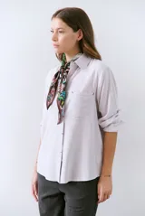 Camisa blanca de manga larga con cuello clásico, cierre de botones frontal y bolsillo de parche en el pecho.