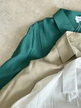 Camisa color beige de corte clásico, con cuello camisero, mangas largas con puños abotonados y cierre frontal con botones.