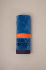 Toalla de algodón color azul con detalle de franja naranja con el nombre de la marca.
