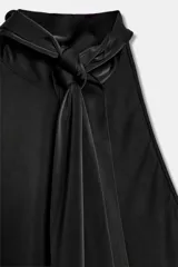 Top de cuello halter confeccionado en tejido satinado, con diseño asimétrico y caída fluida. Presenta lazada ajustable en la espalda.