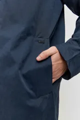 Abrigo largo azul marino de corte recto, con cuello camisero, cierre frontal con botones oscuros y bolsillos laterales ribeteados.