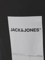 Mochila tipo tote de color negro, con doble asa superior y correas ajustables para llevar en la espalda. Presenta un parche rectangular blanco en el centro con el logo de la marca Jack & Jones.