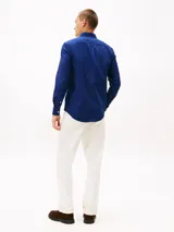 Camisa de corte slim en tejido dobby de algodón elástico, color azul intenso, con cuello con botones y puños redondeados con botón. Presenta el logo de Tommy Hilfiger bordado en el pecho.