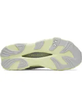 Championes de running Under Armour modelo Halo Racer, color blanco con detalles en amarillo pálido. Presentan una parte superior de malla transpirable, amortiguación UA HOVR+ para retorno de energía y una suela de goma duradera con diseño ergonómico.