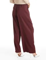 Pantalón tipo palazzo de corte ancho y fluido, confeccionado en tejido sastrero. Presenta tiro alto con doble abotonadura frontal, pinzas decorativas y cintura elástica en la parte posterior. Incluye bolsillos laterales funcionales.