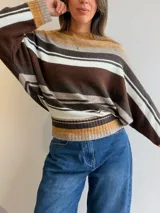 Sweater de tejido de punto con diseño de rayas horizontales en tonos celeste, blanco, gris y marrón. Presenta cuello redondo, mangas tipo murciélago y puños y pretina acanalados.
