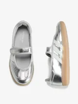 Zapatillas Adidas Samba Jane W de color plateado, con diseño híbrido entre zapatilla y Mary Jane, confeccionadas en piel y material sintético. Presentan tres bandas laterales blancas, tira ajustable con cierre de velcro en el empeine, y suela de goma de tipo caramelo.
