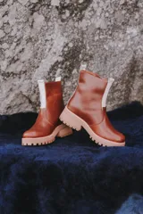 Botas de cuero color blanco con suela chunky y detalles en tono tostado, con cierre lateral y tirador en la parte trasera.