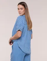 Blusa de silueta amplia de lyocell color azul con diseño de rayas verticales blancas. Cuenta con cuello mao abierto, abotonadura frontal, mangas cortas caídas y lazos en el ruedo para anudar al frente.