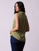 Blusa color crema sin mangas, con cuello camisero, cierre frontal con botones y bolsillo de crochet.