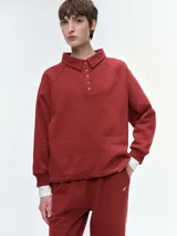 Buzo de cuello polo con escote abotonado, manga larga raglán y puños acanalados. Confeccionado en tejido suave y confortable.